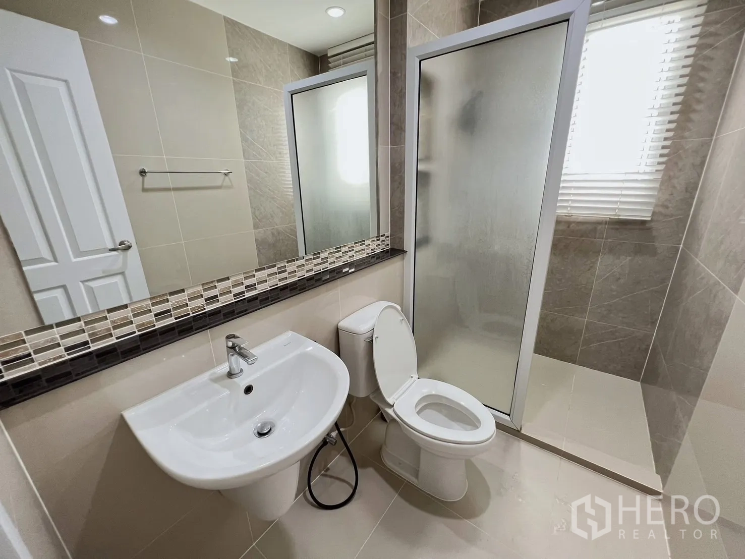 Detached House for rent or sale in Khlong Luang, Pathum Thani - Neutral-tone bathroom with glass shower enclosure, sink and toilet.