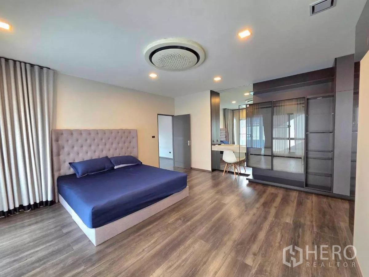 Detached House for rent in Bang Phli, Samut Prakan - Spacious master bedroom with tufted headboard, built-in wardrobe and vanity on wood flooring.
