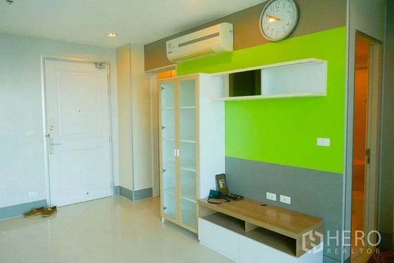 Condominium for rent or sale in Khlong San, Bangkok - Living room media wall with glass cabinet, shelving and split-type air conditioner.