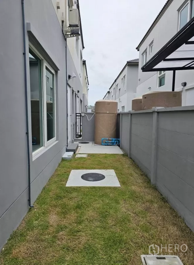 Detached House for rent in Bang Phli, Samut Prakan - Narrow side yard with grass, utility zone and water storage tank.