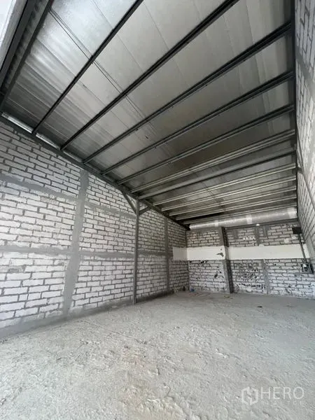 Retail Space for rent in Khlong Toei, Bangkok - Unfinished retail interior with exposed brick walls, steel truss ceiling, and concrete subfloor.