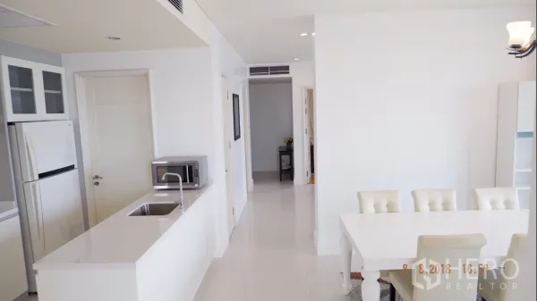 公寓 出租在Khlong Toei, Bangkok - 开放式厨房配白色中岛水槽，旁为六人餐桌。