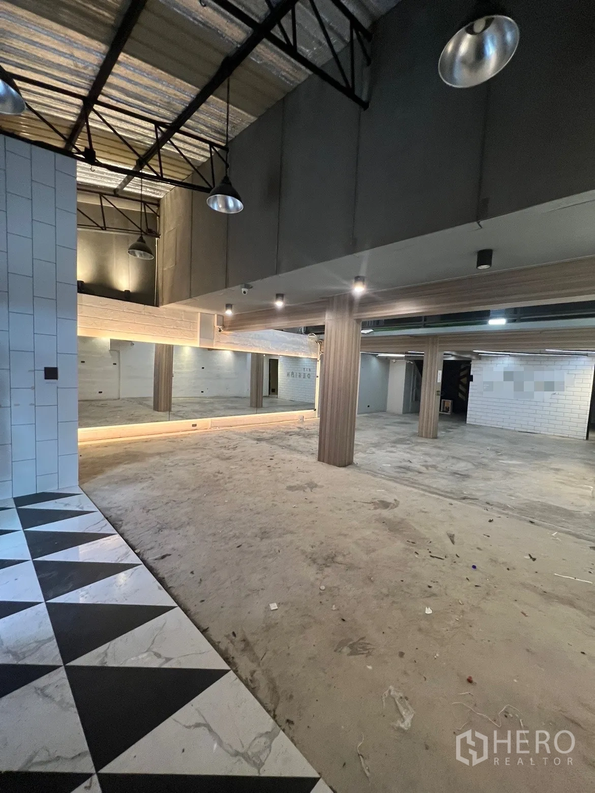 零售空间 出租在Phaya Thai, Bangkok - 一层开放式空间，层高挑高，金属梁架，镜面墙与柱体，入口三角拼花地砖。