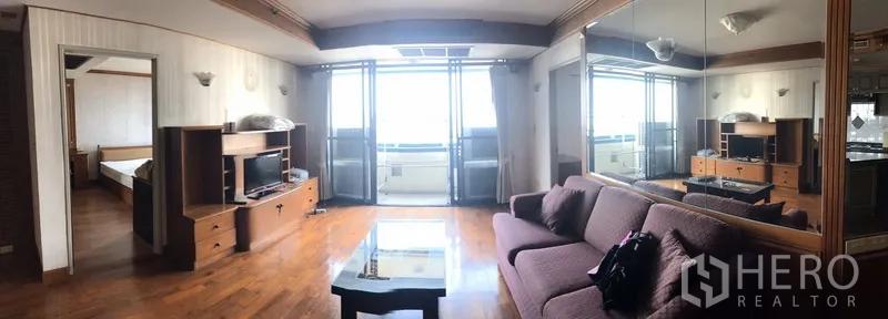 公寓 出租在Watthana, Bangkok - 全景客厅，展示通往阳台的门与镜面特色墙。