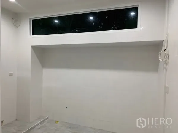 Townhouse for sale in Yan Nawa, Bangkok - White built-in niche wall with a high horizontal window in a renovated room.