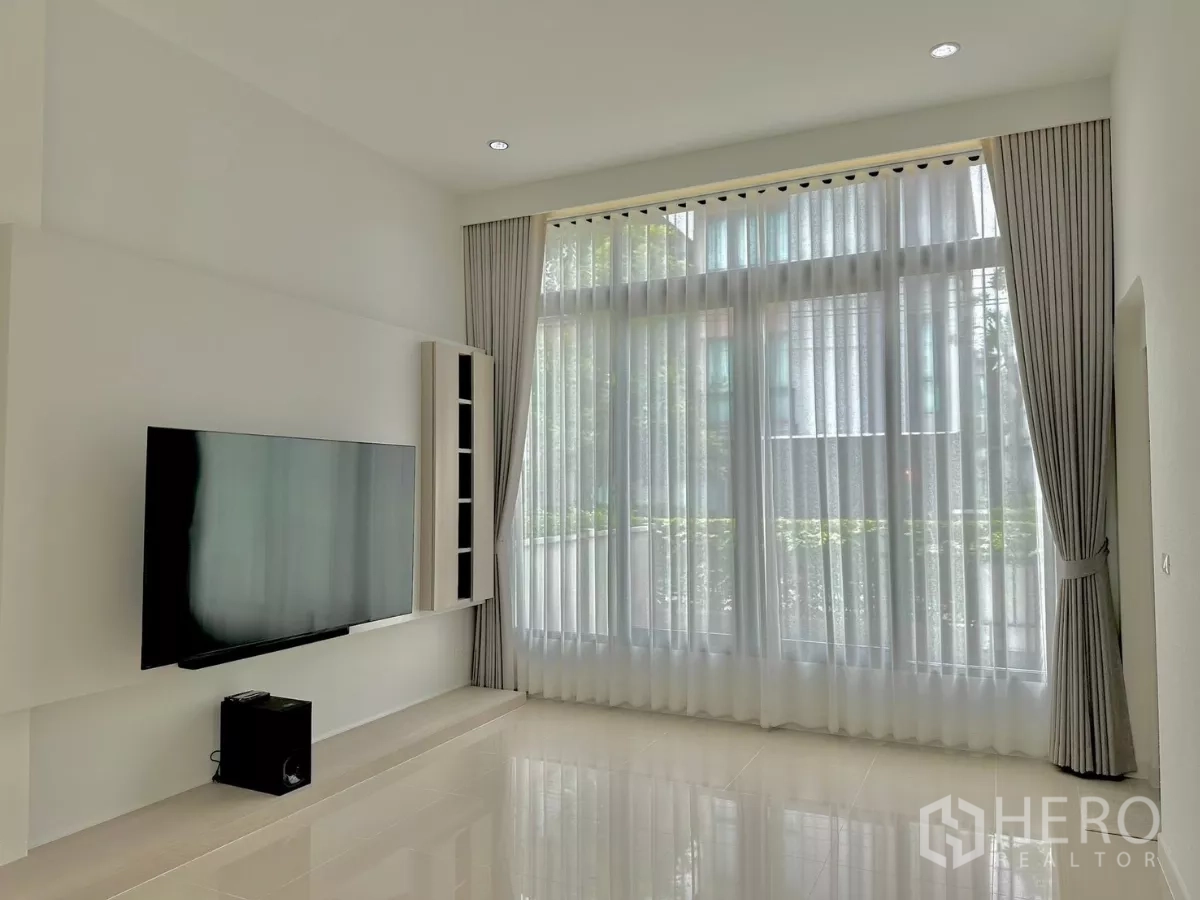 独立式住宅 出租或出售在Prawet, Bangkok - 挑高客厅采光充足，落地窗帘与壁挂电视。