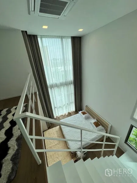 Detached House for rent - Mezzanine sitting area with a sofa and patterned rug overlooking the space below.
