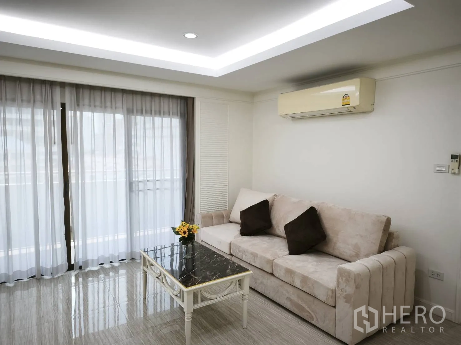 คอนโด for rent in Watthana, Bangkok - มุมโซฟาใต้ไฟดาวน์ไลท์ ข้างประตูกระจกบานเลื่อนและเครื่องปรับอากาศติดผนัง