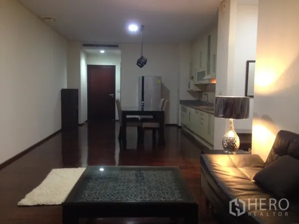 公寓 出租在Watthana, Bangkok - 宽敞玄关通向餐区与客厅，暖色灯光与木地板。