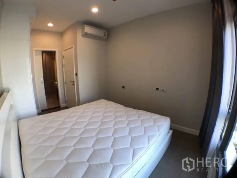 Condominium for rent in Khlong Toei, Bangkok - Bedroom with air conditioning and doorway to an ensuite bathroom.