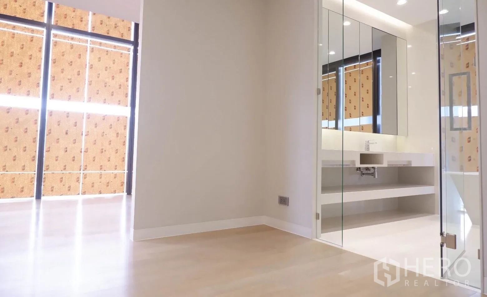 Condominium for sale in Watthana, Bangkok - Bedroom corner opening to a glass-enclosed vanity and large mirrored cabinets.