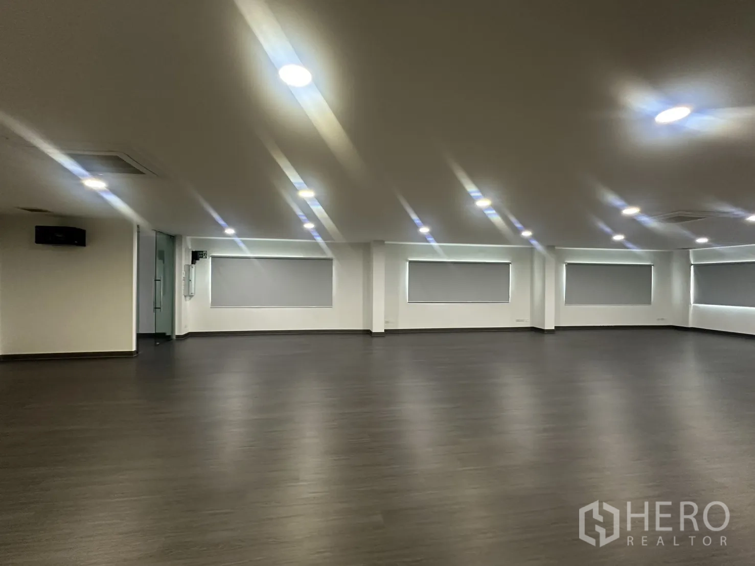 办公室 for rent in Yan Nawa, Bangkok - 开放工作区，玻璃入户门、周边多扇带卷帘的窗户与均匀的嵌灯照明。