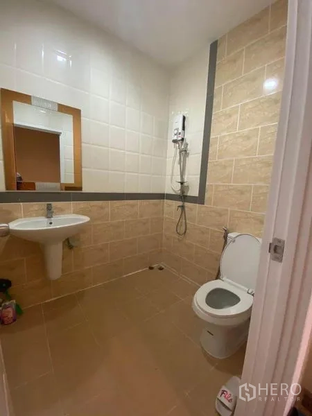 Townhouse for sale in Saphan Sung, Bangkok - Clean bathroom with shower, water heater, toilet and sink set in beige tiles.