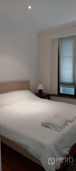 Condominium for rent in Sathon, Bangkok - Bright bedroom with a double bed, bedside lamp and window blinds.