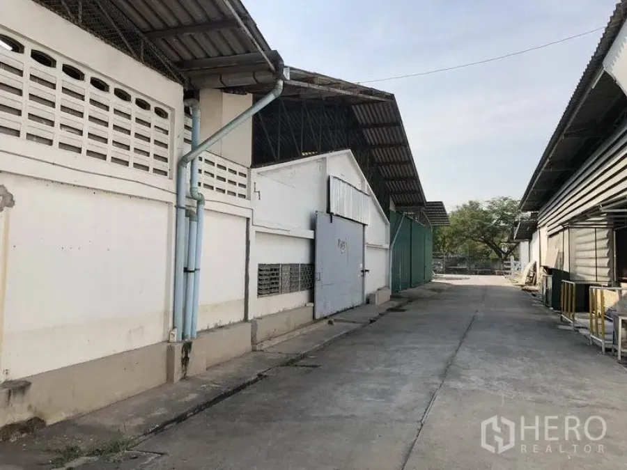 คลังสินค้า ให้เช่าในMueang Pathum Thani, Pathum Thani - ทางสัญจรระหว่างอาคารโกดัง ประตูบานสไลด์ หลังคาเมทัลชีท และลานคอนกรีตกว้างสำหรับรถบรรทุก ในอำเภอเมืองปทุมธานี