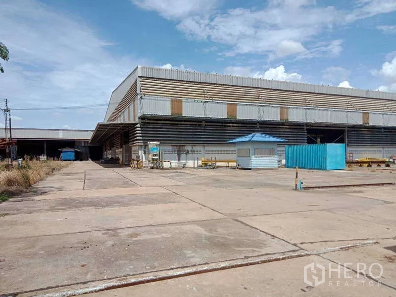 Factory for sale in Chachoengsao - Paved approach to the factory facade with a blue kiosk and storage container.