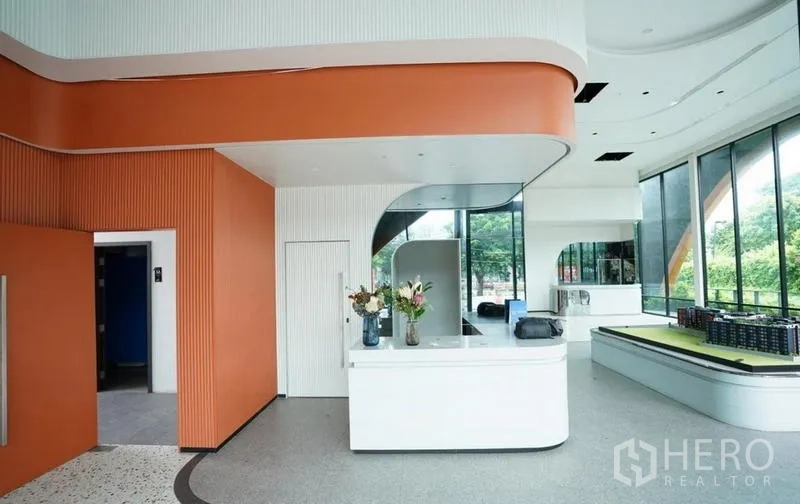 Standalone for rent in Bang Na, Bangkok - Reception zone with orange accent ceiling and white counter in a glassy lobby.