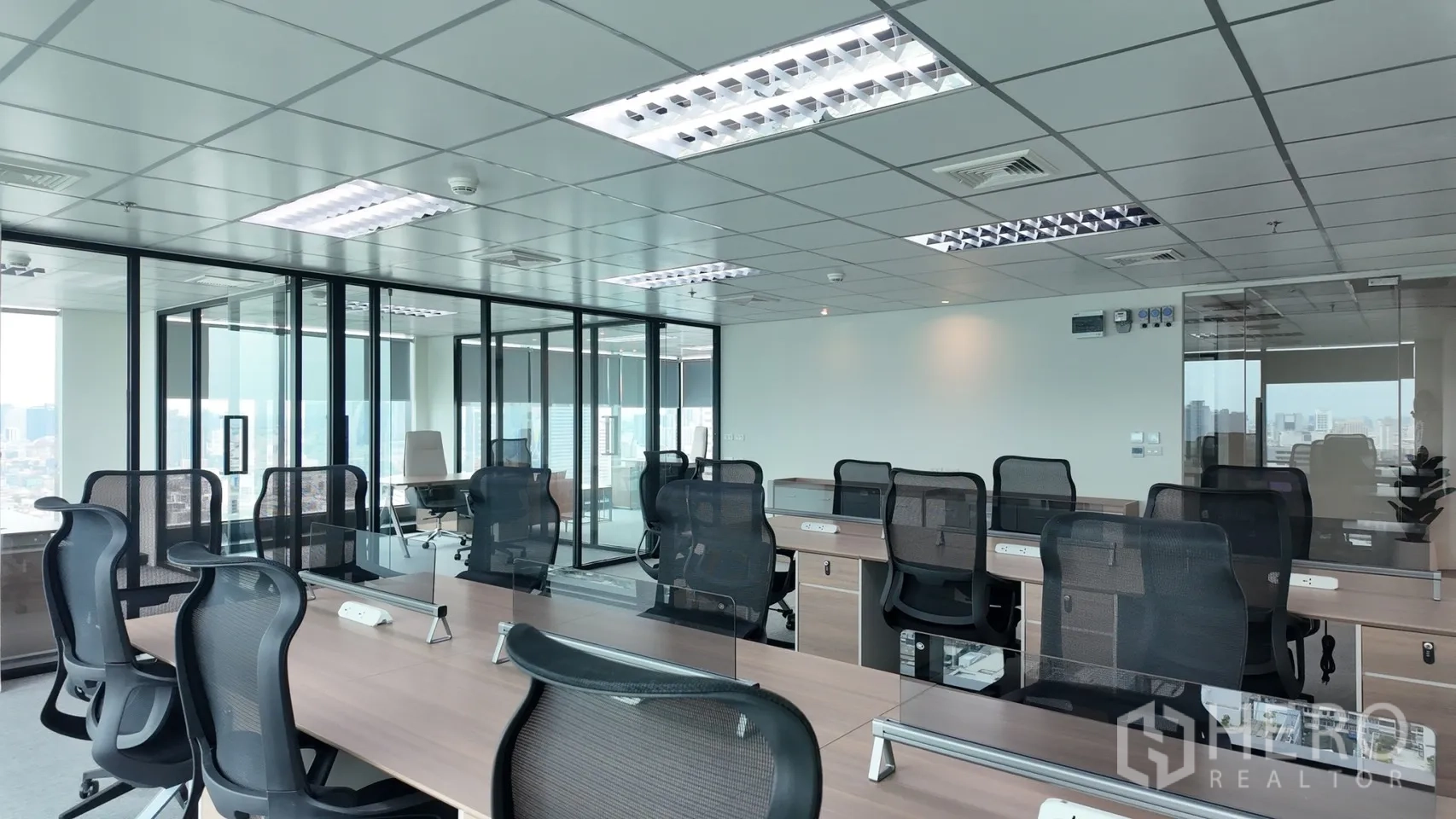Office Space for rent in Din Daeng, Bangkok - Spacious office floor with shared desks, carpet tiles, and ceiling lighting beside glass meeting rooms.