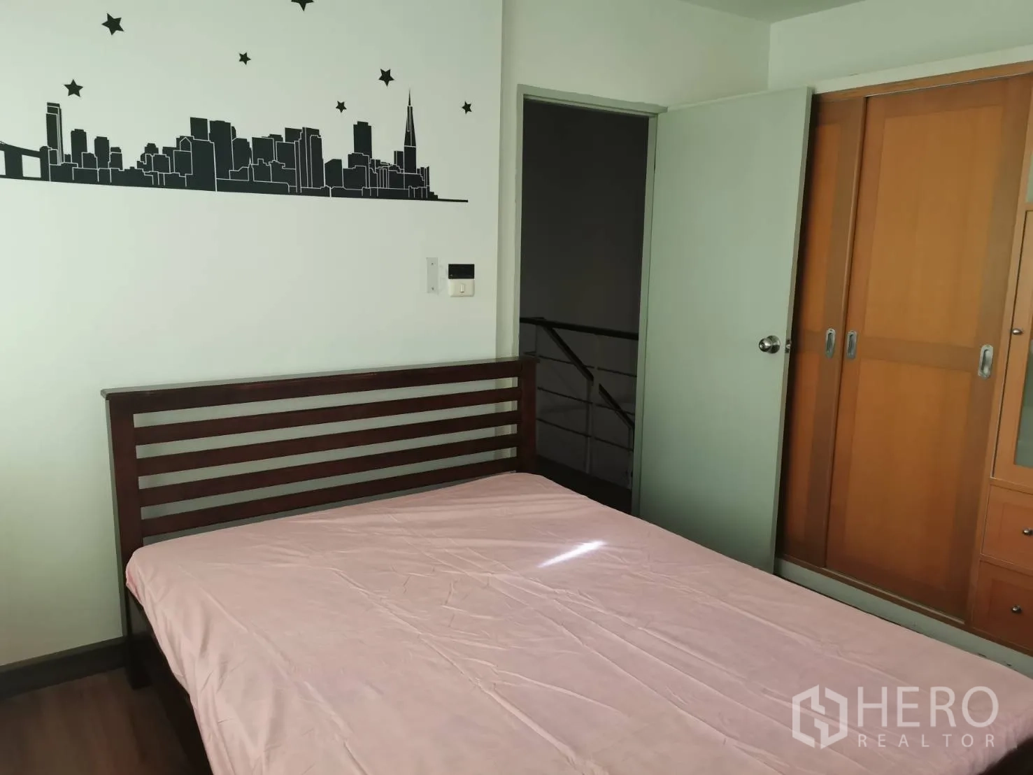 Townhouse for rent or sale in Yan Nawa, Bangkok - Secondary bedroom with bed, sliding-door wardrobe and cityscape wall decal.