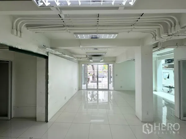 零售空间 出租在Bang Rak, Bangkok - 细长型展售区，外露天花管线，玻璃入口面向街道。