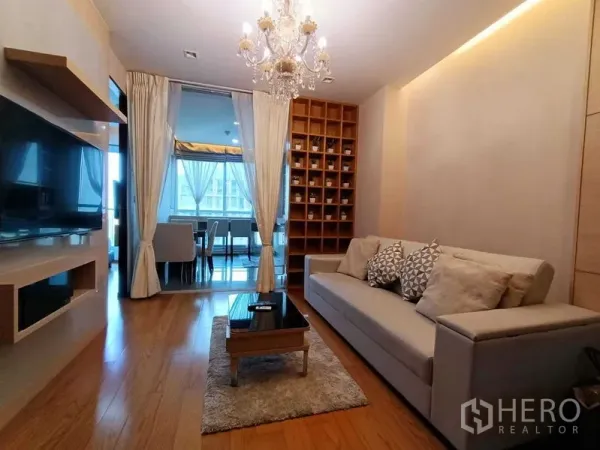 Condominium for rent in Ratchathewi, Bangkok - Living room facing the dining area with sliding glass door, display shelving and modern sofa.
