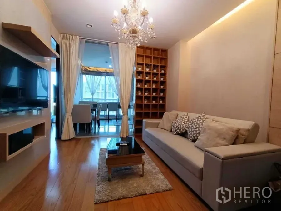公寓 出租在Ratchathewi, Bangkok - 客厅望向餐区，推拉玻璃门分隔，展示柜与现代沙发一应俱全。