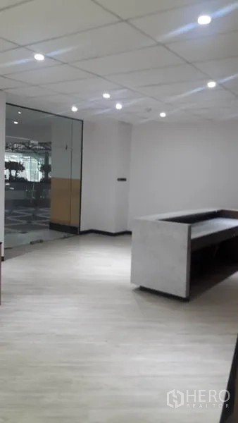 Office Space for rent in Huai Khwang, Bangkok - View from inside reception toward the glass entrance with neutral walls and spotlights.