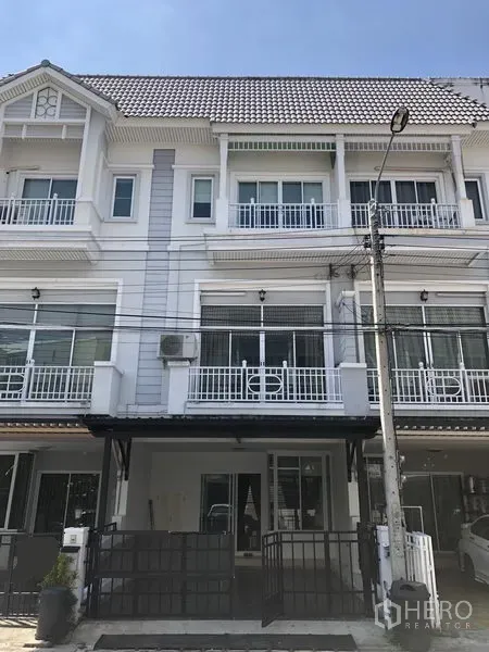Townhouse for rent in Prawet, Bangkok - Three-storey townhouse exterior with white facade, balconies and gated parking.