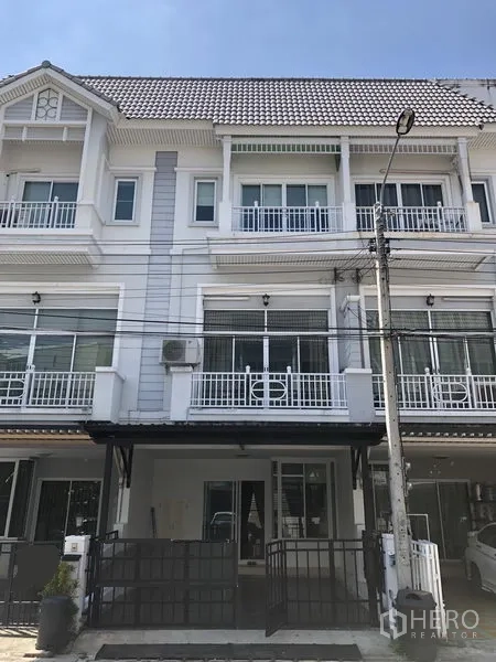 Townhouse for rent in Prawet, Bangkok - Three-storey townhouse exterior with white facade, balconies and gated parking.