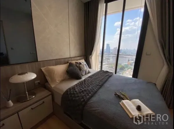Condominium for rent or sale in Phaya Thai, Bangkok - Corner bedroom showcasing panoramic Bangkok skyline through tall glass windows.
