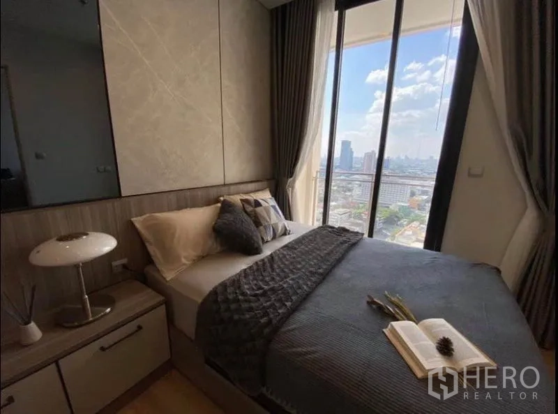 Condominium for rent or sale in Phaya Thai, Bangkok - Corner bedroom showcasing panoramic Bangkok skyline through tall glass windows.