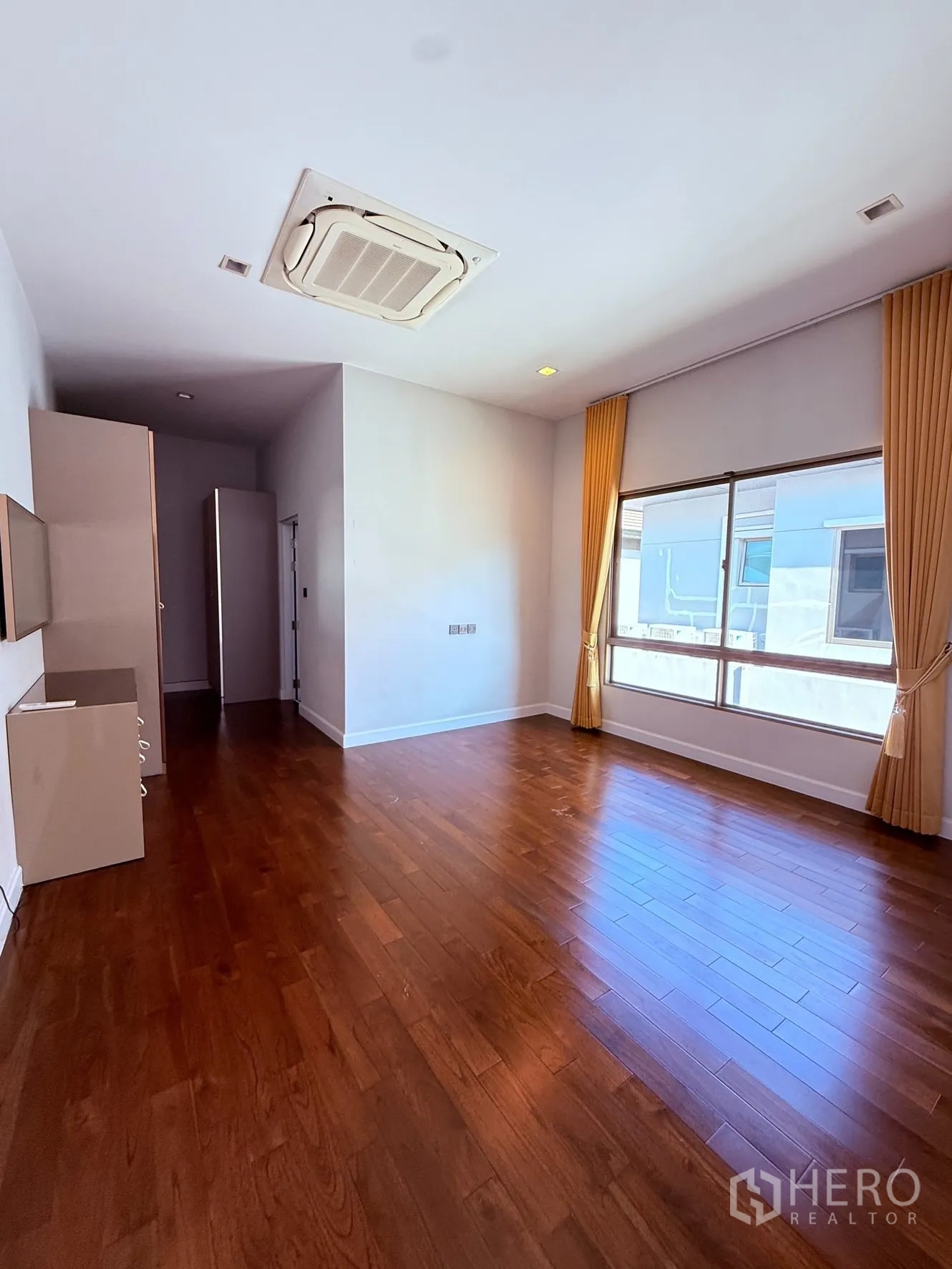 Detached House for rent or sale in Prawet, Bangkok - Generous bedroom with hardwood flooring, large window, and ceiling cassette air conditioning.