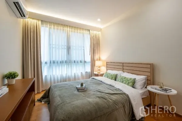 Condominium for sale - Cozy bedroom with double bed, soft lighting and large curtained window.