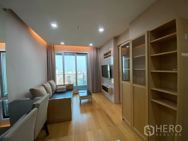 公寓 出租在Ratchathewi, Bangkok - 客厅设沙发、壁挂电视，落地窗与阳台，可观城市景色。