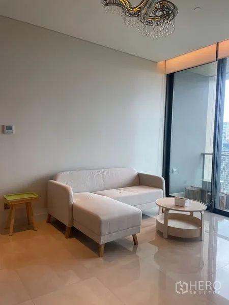 Condominium for rent in Pathum Wan, Bangkok - Cozy corner with L-shaped sofa, side table and balcony access under a modern chandelier.