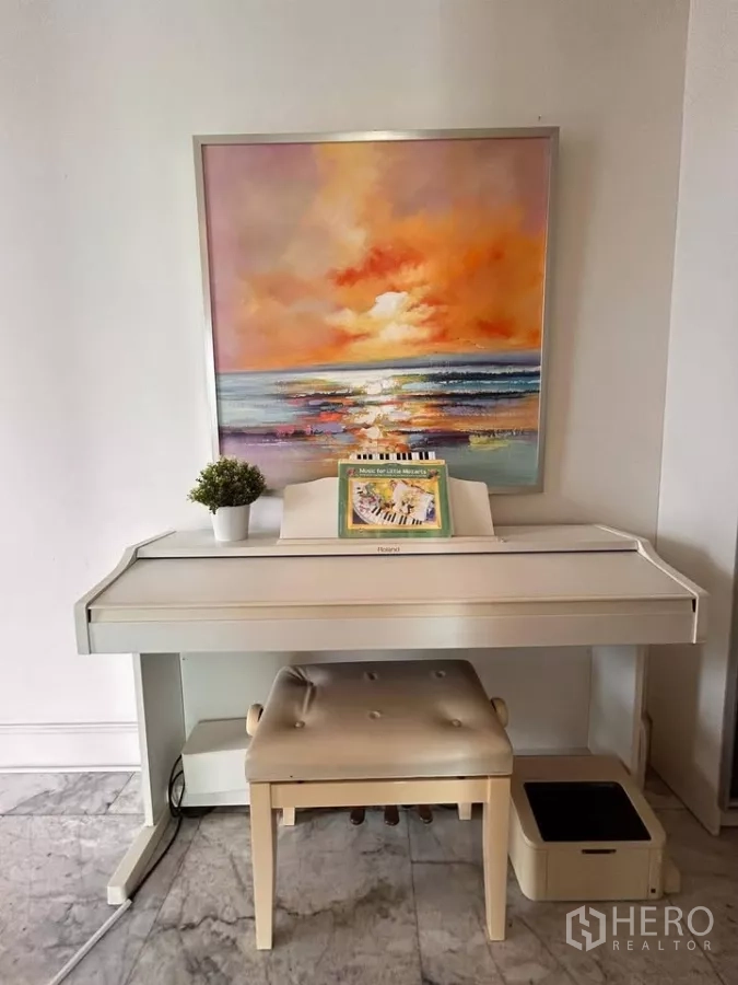 Condominium for sale in Watthana, Bangkok - White digital piano with bench beneath a colorful seascape painting.