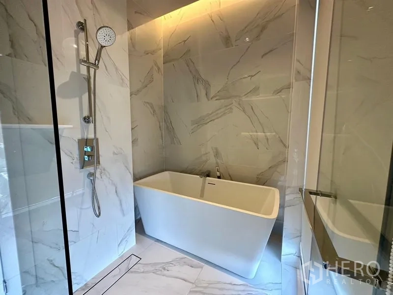 Condominium for rent - Luxury bathroom featuring a freestanding bathtub, marble-look tiles, and a glass shower.
