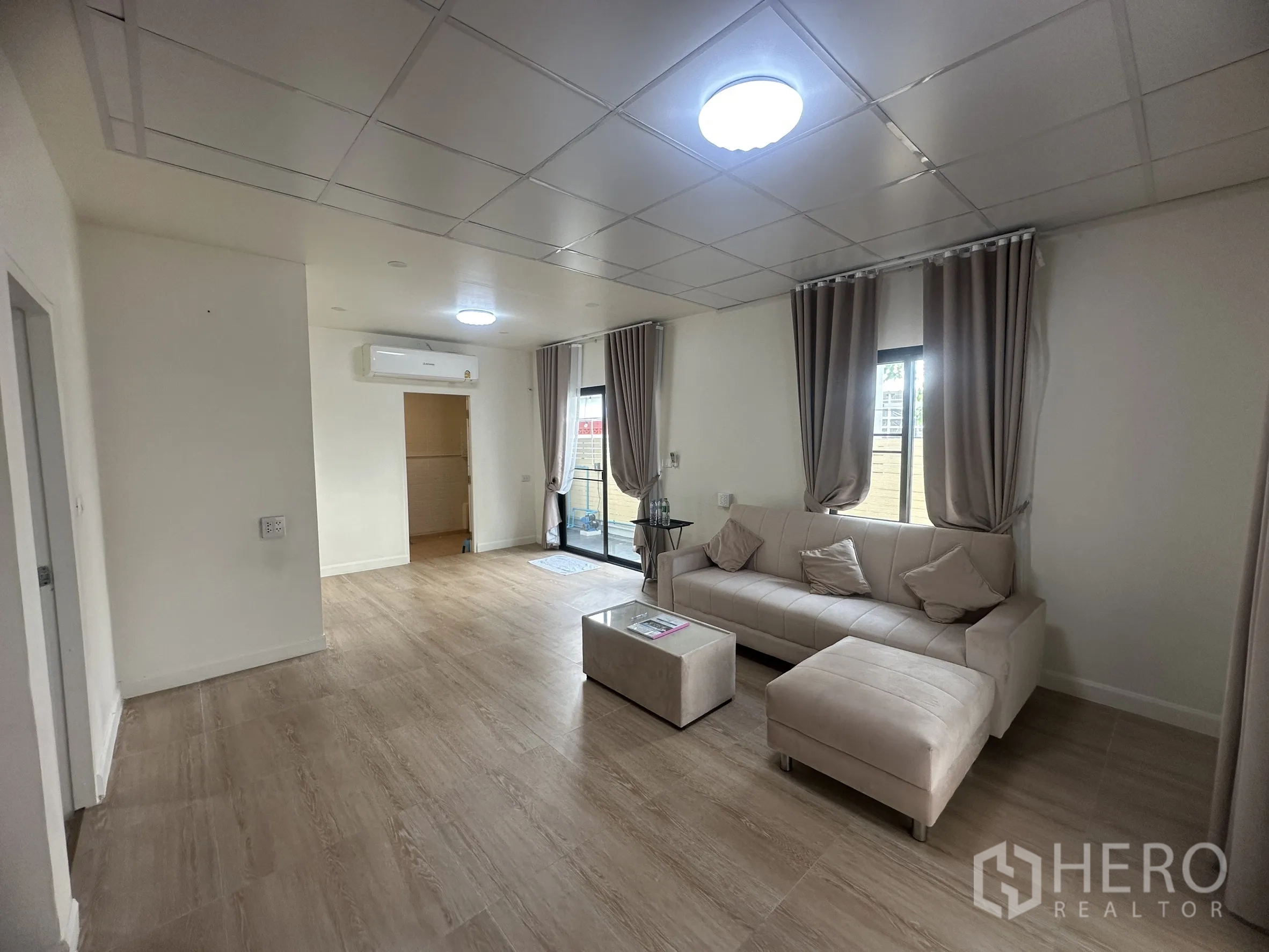 Townhouse for sale in Lam Luk Ka, Pathum Thani - Spacious lounge with sliding doors to the front and neutral decor.