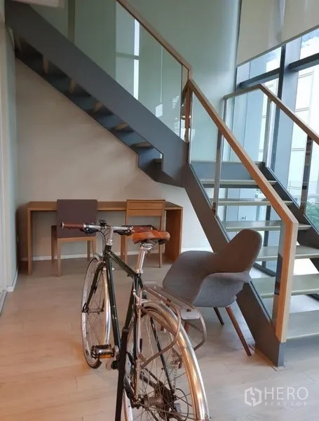 公寓 出租或出售在Watthana, Bangkok - 楼梯下工作角，书桌与休闲椅，临近落地窗与阳台出口