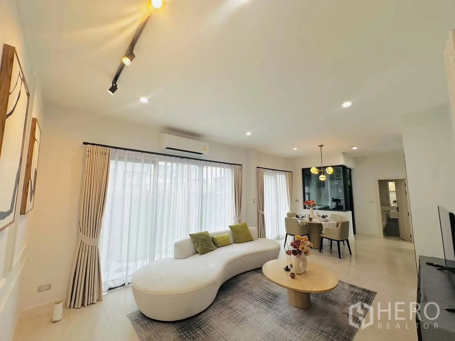 联排别墅 for rent in Suan Luang, Bangkok - 开放式客餐厅，弧形沙发、圆形茶几与大面积落地窗。