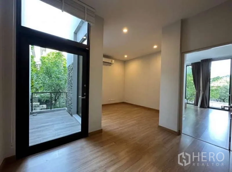 Townhouse for rent in Lat Phrao, Bangkok - Upper-floor family area opening to a small terrace, wood floors and recessed lighting.