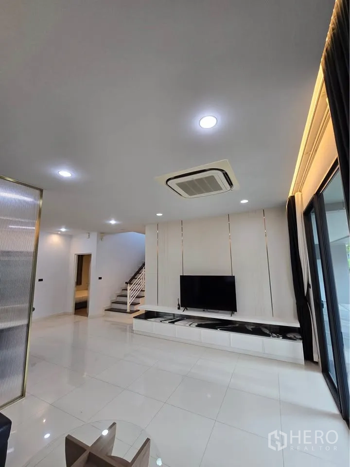 Detached House for rent in Bang Kapi, Bangkok - Living room with TV feature wall and staircase.