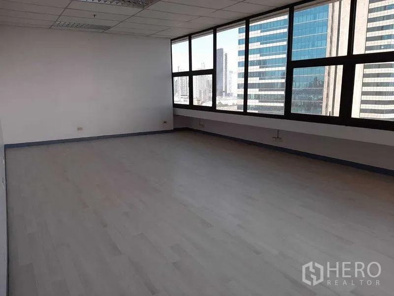 Office Space for rent in Khlong Toei, Bangkok - Open office lined with tall windows overlooking high-rise buildings.