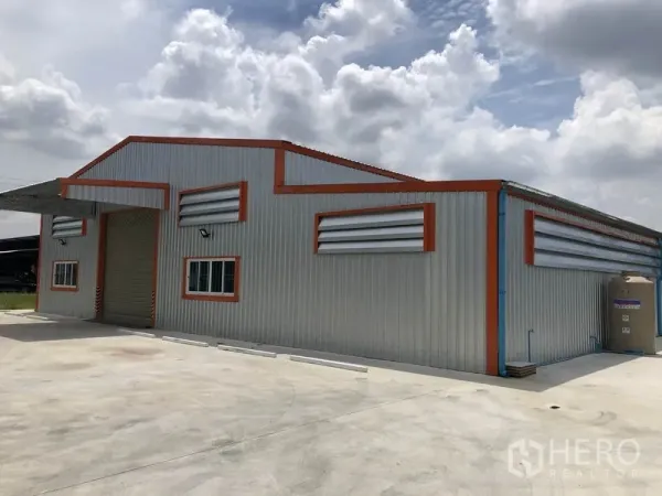 Warehouse for rent in Mueang Nonthaburi, Nonthaburi - Side view of the warehouse highlighting ventilation louvers, metal siding and service area toward the rear.