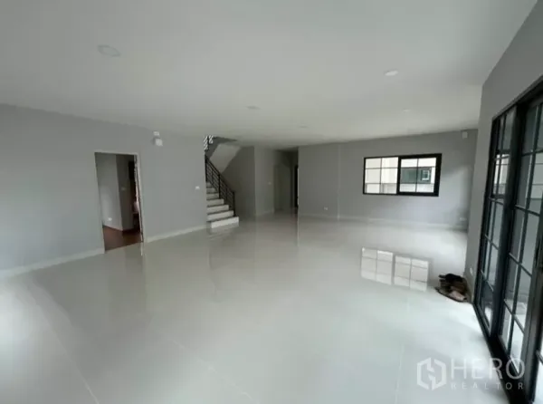 Detached House for rent in Bang Phli, Samut Prakan - Spacious open-plan living room with glossy tile floors, staircase and large windows with sliding doors.
