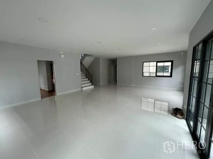 Detached House for rent in Bang Phli, Samut Prakan - Spacious open-plan living room with glossy tile floors, staircase and large windows with sliding doors.