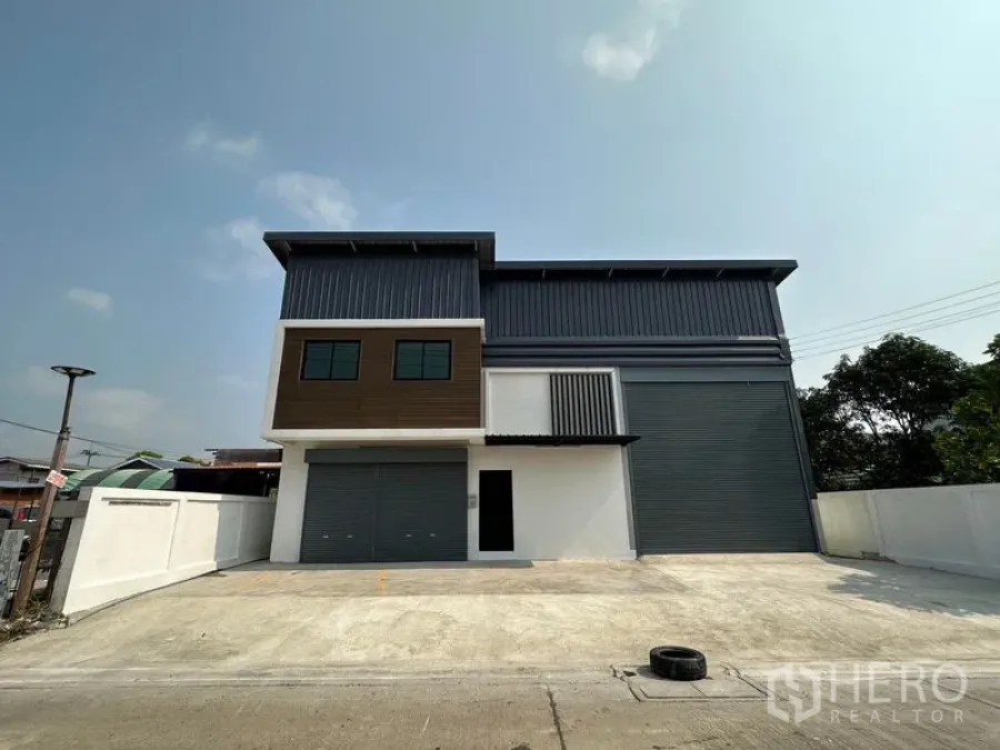 คลังสินค้า ให้เช่าในLam Luk Ka, Pathum Thani - มุมมองเต็มอาคารโกดังสองชั้นใหม่ ประตูม้วนคู่ และลานจอดรถกว้างในลำลูกกา ปทุมธานี