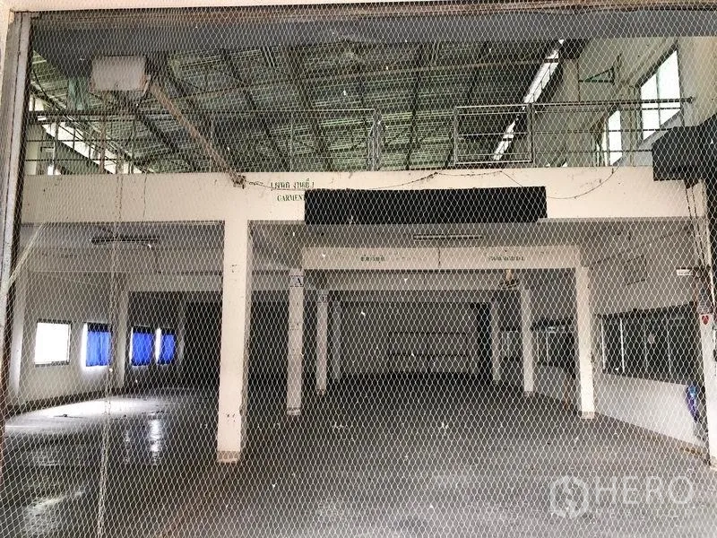 工厂 出售在Lam Luk Ka, Pathum Thani - 通过安全网看到的大型生产大厅，设有夹层