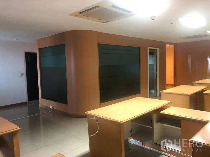 Office Space for rent in Sathon, Bangkok - Open-plan office with built-in wood desks, curved tinted-glass partition, tiled floors and ceiling air-conditioning.