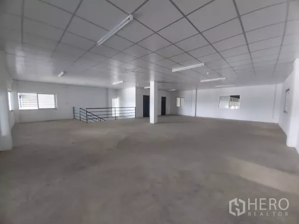 Warehouse for rent in Bang Bo, Samut Prakan - Open-plan office floor with railing, fluorescent lights and ample natural light.